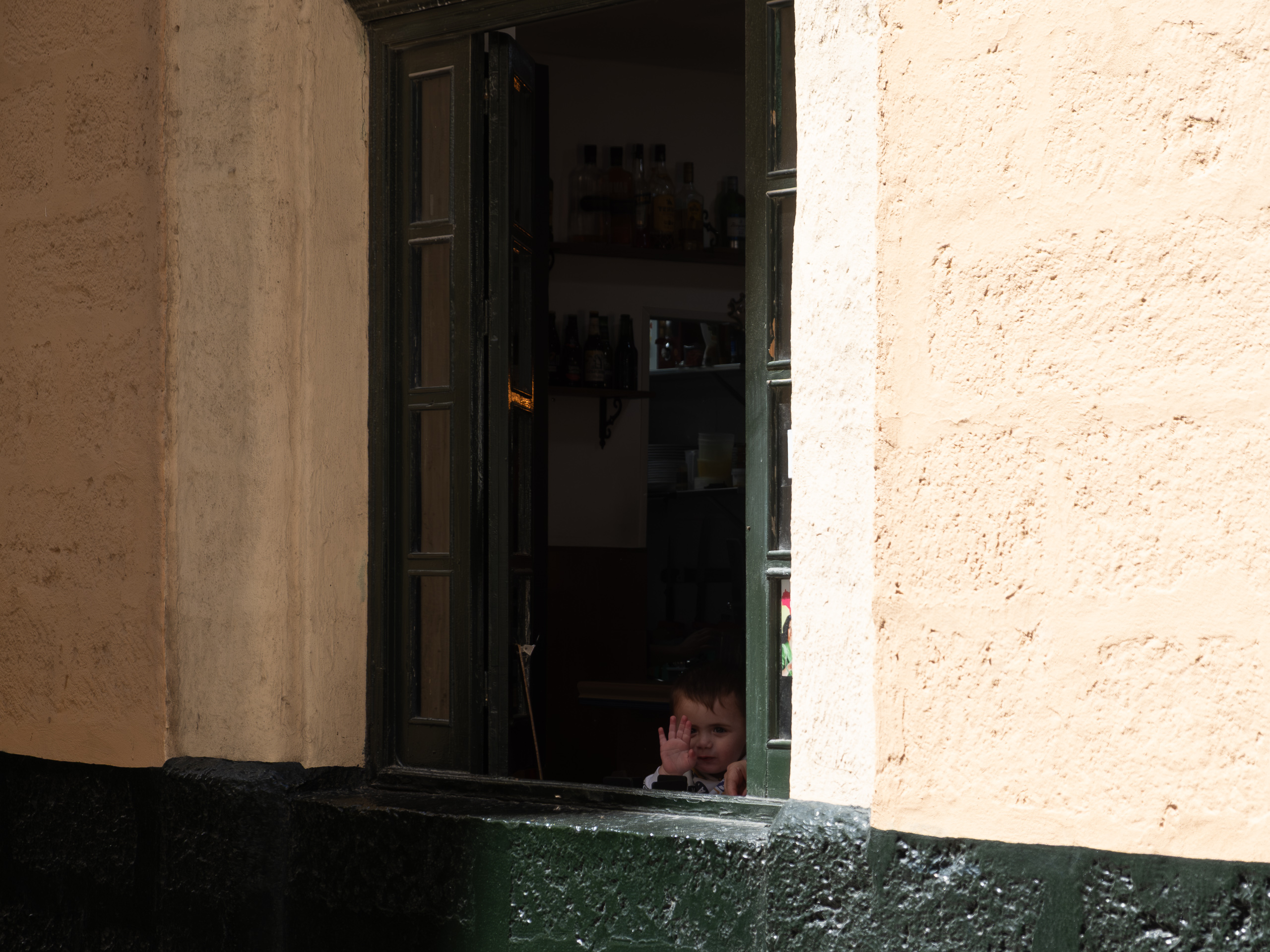 Ein Kind winkt aus einer Haustür